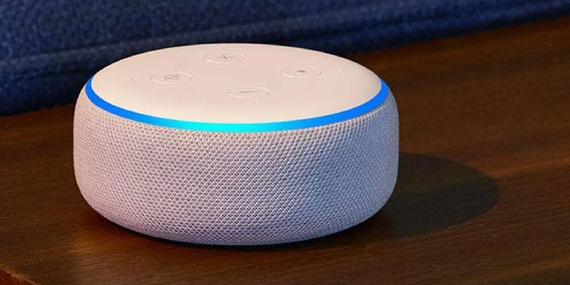 Thiết bị trợ lý ảo Amazon Alexa màu trắng đặt trên bề mặt gỗ.
