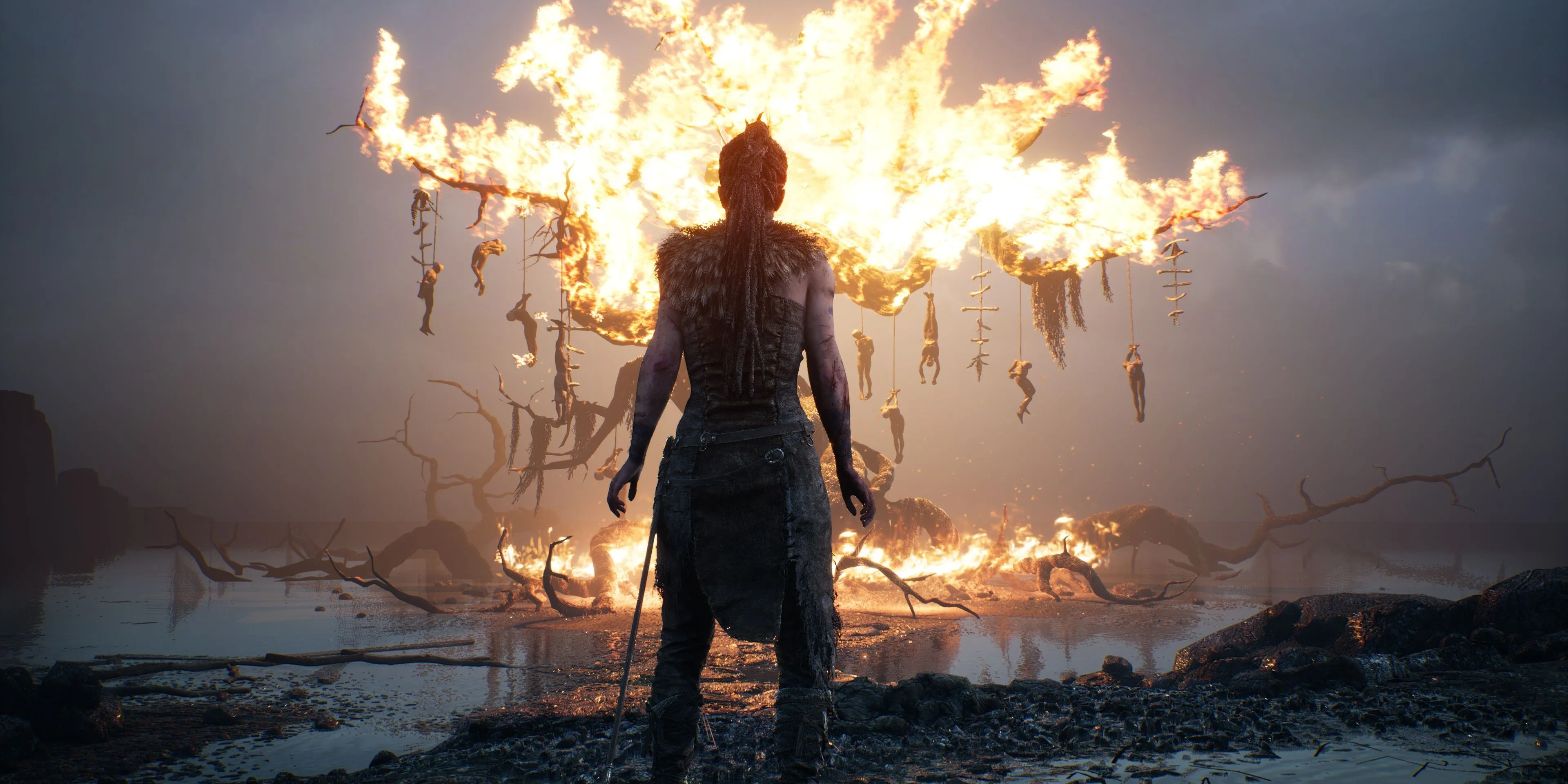 Senua đứng trước cây cháy, biểu tượng của cuộc chiến nội tâm trong Hellblade: Senua's Sacrifice.